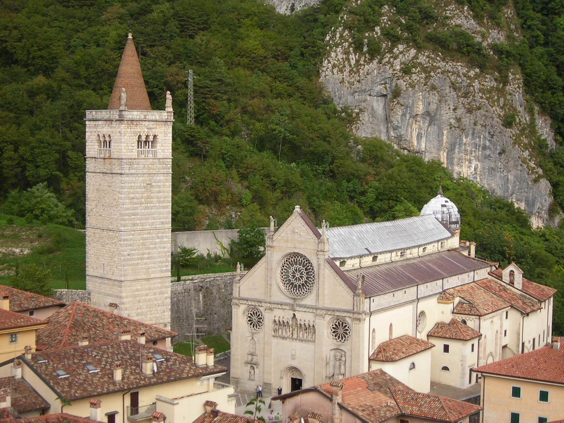 Gemona cathedral and bell tower beneath green mountain cliffs, seen from above