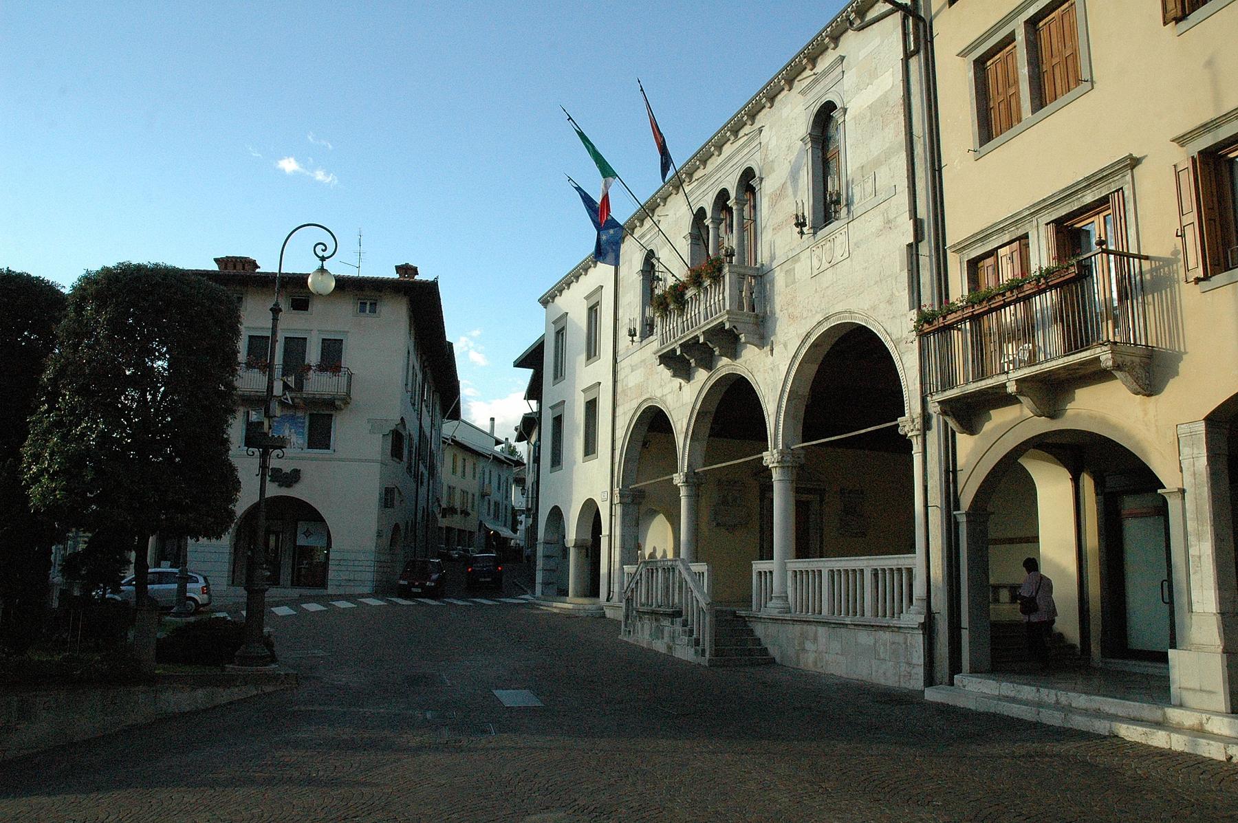 Arcaded Renaissance town hall with flags on a historic street in Gemona